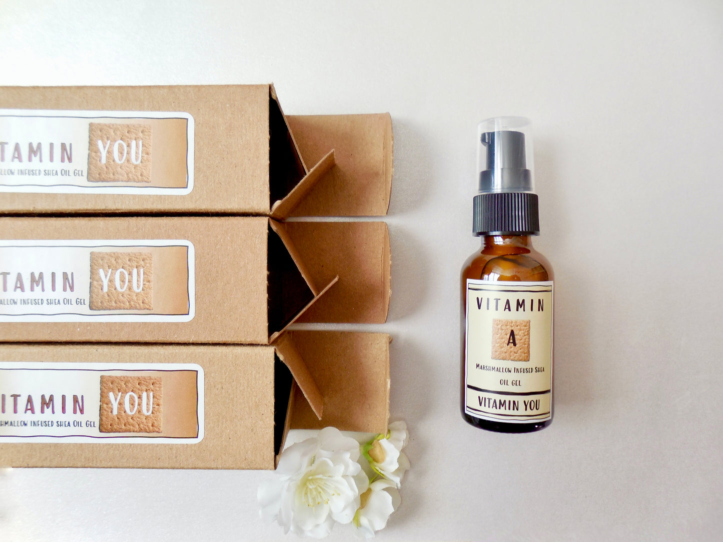 3 Kraft boxes of the marshmallow shea oil gel opening to one bottle of the product.