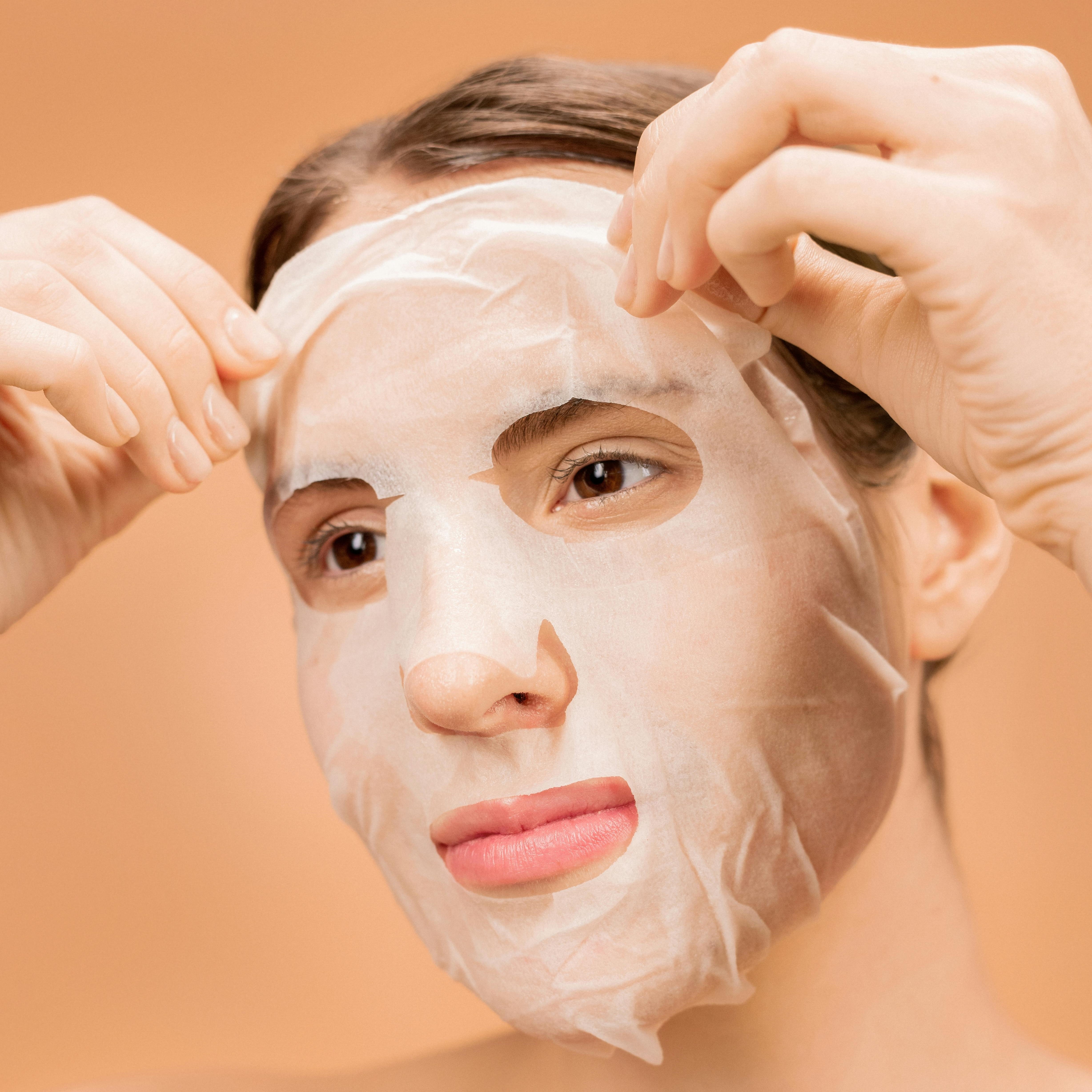 Woman applying a facial sheet mask into face.