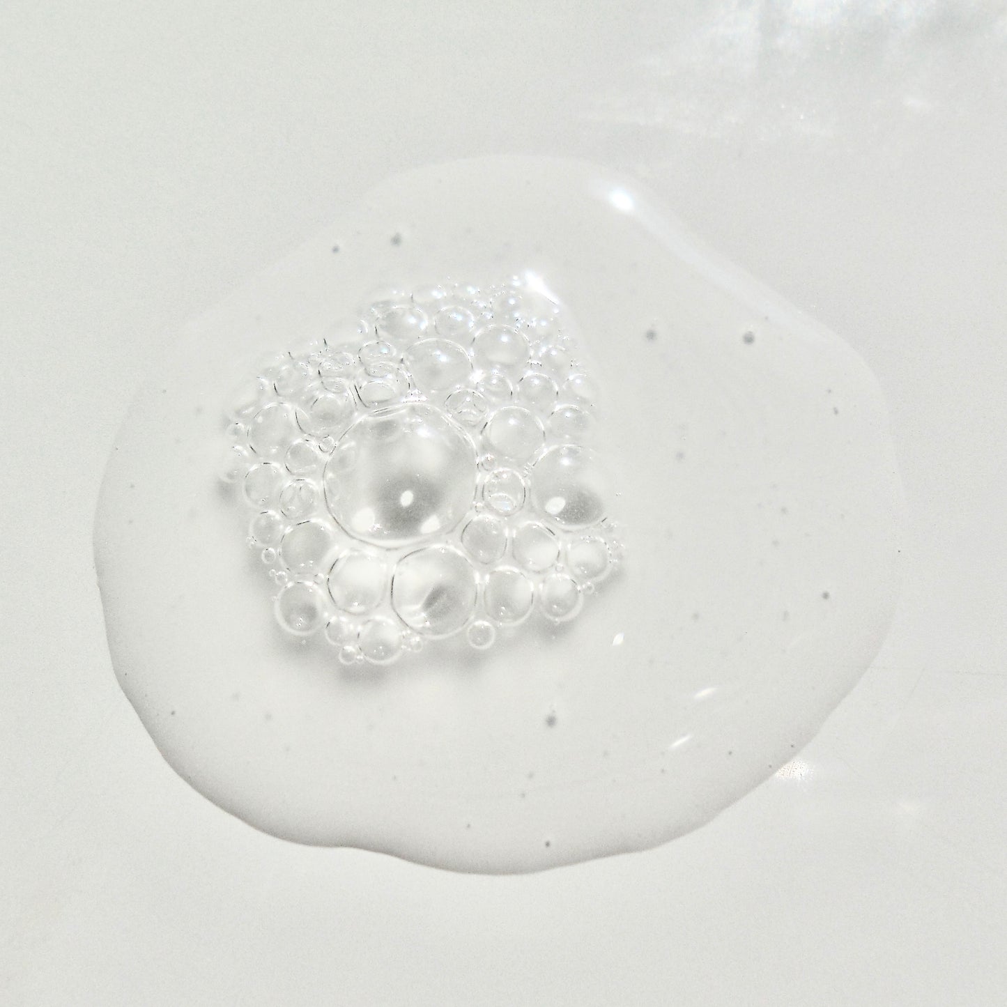 Close-up of a white liquid with bubbles on a light gray background