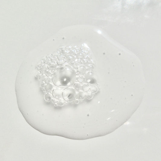 Close-up of a white liquid with bubbles on a light gray background