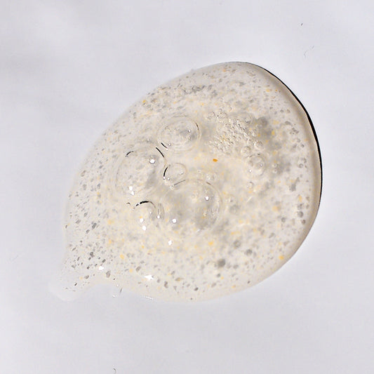 Skincare texture shot of the fruit acid exfoliant with bubbles. There are tiny specs of pumpkin fruit powder suspended in the gel.