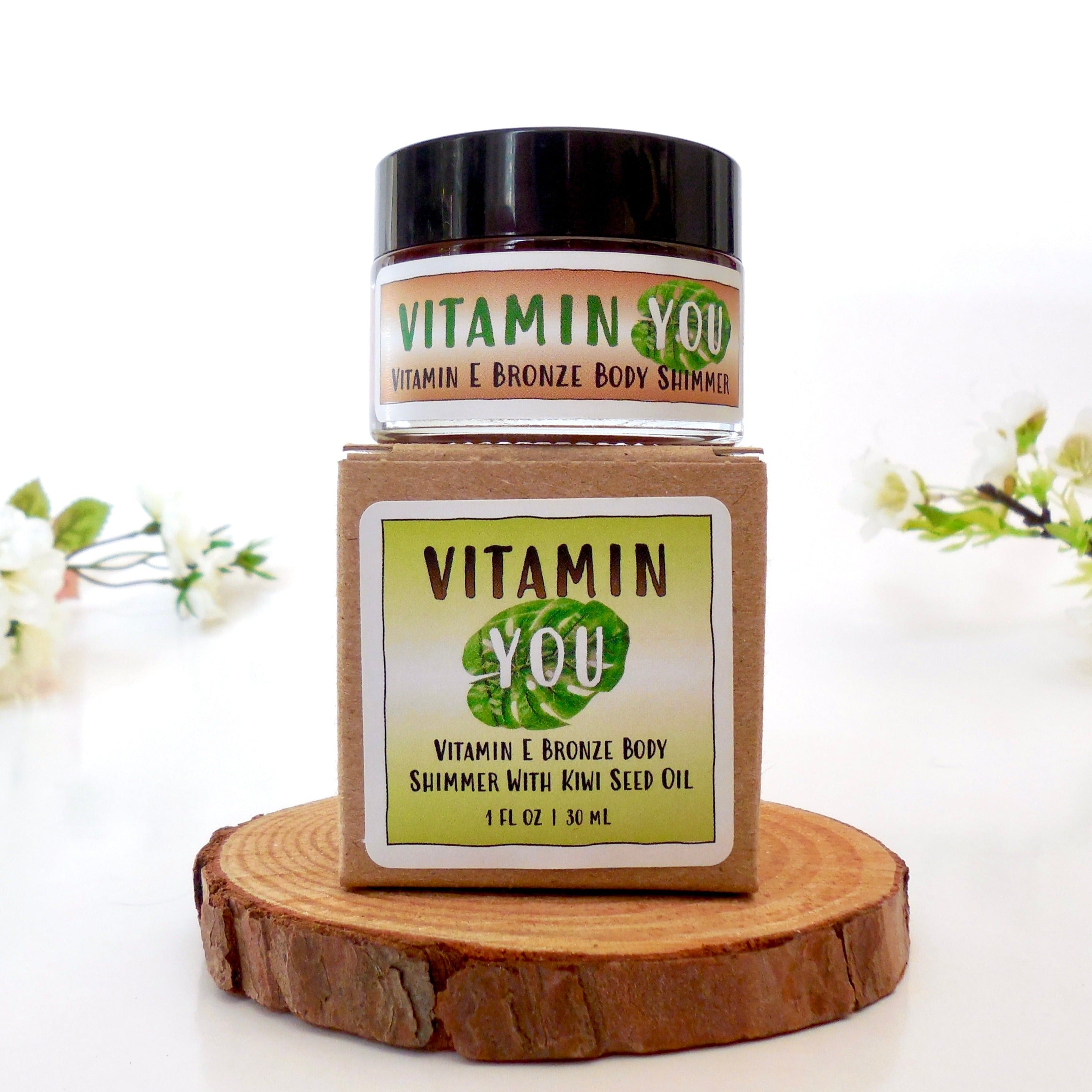 Jar and box of the Vitamin You Vitamin E Bronze Body Shimmer with a lime green tropical plant and bronze theme